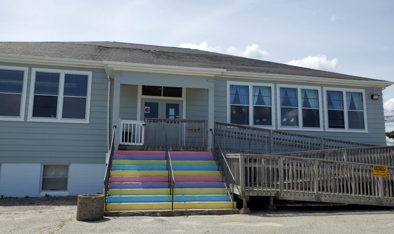 The outside of Queens County Daycare on a sunny day. The building has rainbow steps.