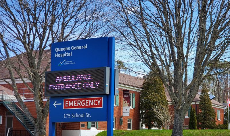 Sign points to hospital emergency room entrance at Queens General Hospital on a sunny day