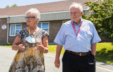 A woman walks between two men down a driveway on a sunny day