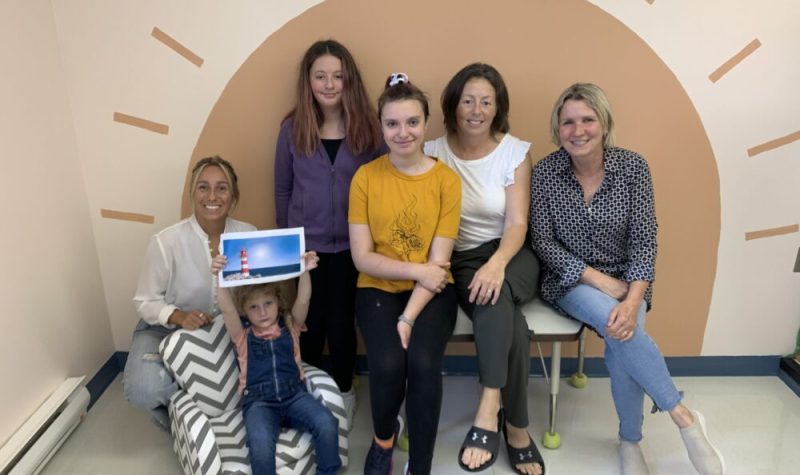 Un groupe de trois femmes et de trois enfants d'âge primaire et secondaire sourient à la caméra.