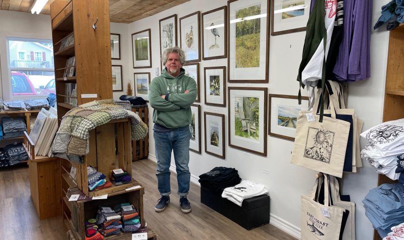 A man standing in a room with displays and lots of art handing on the walls.