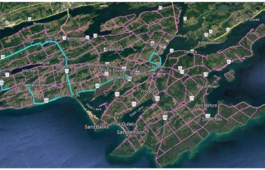 A close in satellite green and blue map of the Prince Edward County landmass. Its road grid is present and shaded turquoise blue and purple in various parts.