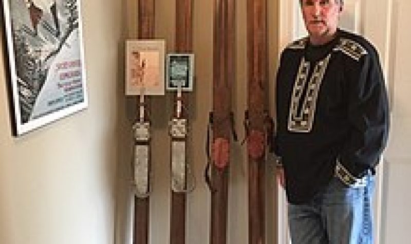 A man standing in a room beside four wooden pillars.