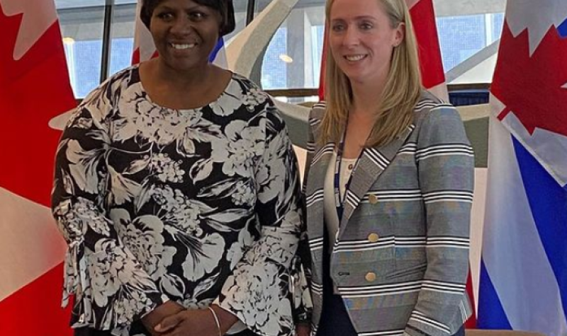 Two people in patterned shirts stand in front Canadian and Ontario flags.