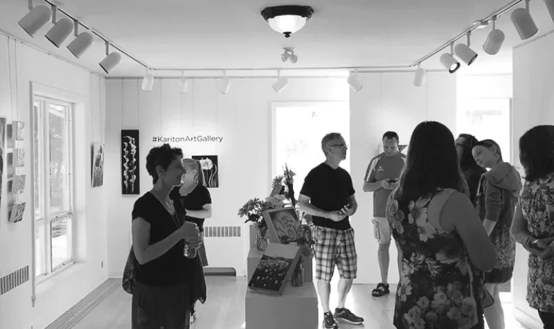 A black and white photo of inside the Kariton art gallery while patrons look at the art.