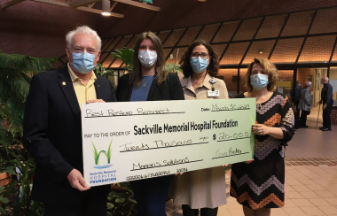 Four people wearing masks hold a giant cheque made out to the Sackville Memorial Hospital Foundation