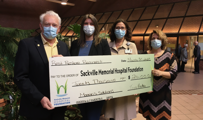 Four people wearing masks hold a giant cheque made out to the Sackville Memorial Hospital Foundation
