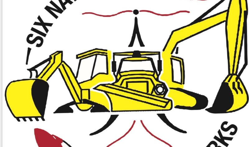A yellow drawing of a excavator reaching out both claw handles on both left and right sides. The words Six Nations Public Works surrounds the excavator with a drawing on a white and red feather also outlining the excavator.