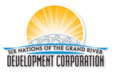 Six Nations of the Grand River Development Corporation spelled in black text under a grey turtle shell with a golden circle surrounding the shell. All on a white backdrop.