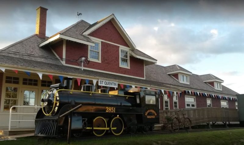 Une photographie de la gare avec un train ancien en premier plan