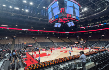 An arena with several seats and a court with colours of beige and red.