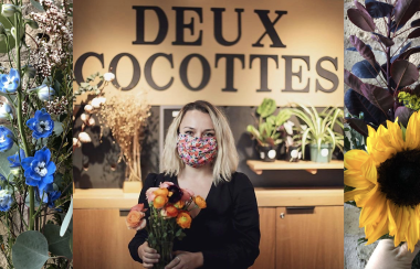 Liliane, debout devant un comptoir de plantes, tien un bouquet de fleurs dans ses mains.