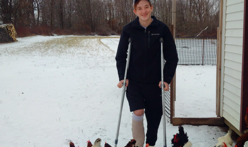 Wesley Weber stands on crutches and is surrounded by chickens on his family's farm in Arthur, Ontario.