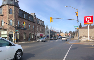 The intersection of St. David Street North and St. Andrew Street in Fergus is seen on a sunny day with a white car on the left waiting at the intersection light.