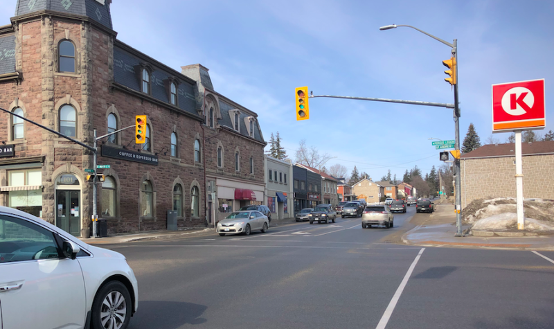 The intersection of St. David Street North and St. Andrew Street in Fergus is seen on a sunny day with a white car on the left waiting at the intersection light.