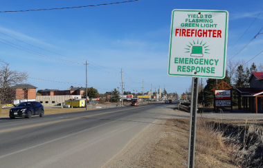 A sign about firefighter green lights next to the highway near Fergus, Ontario on a sunny day
