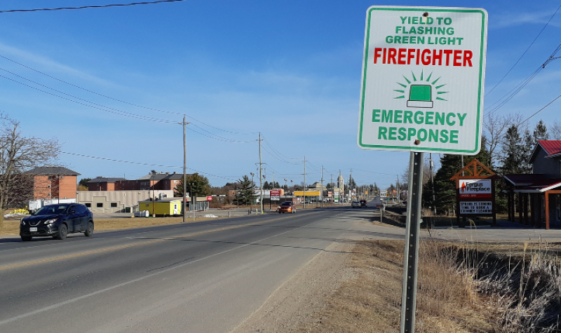 A sign about firefighter green lights next to the highway near Fergus, Ontario on a sunny day