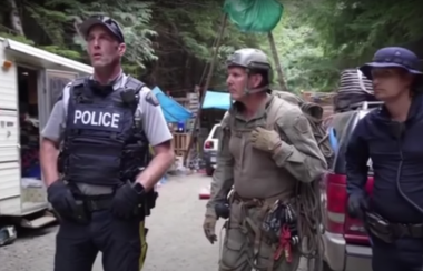 Three police officers are seen in a video screen shot at the protest at Fairy Creek