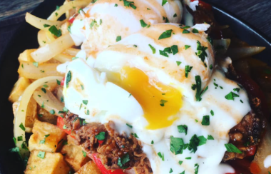 A close up of eggs, fries and different toppings on a plate