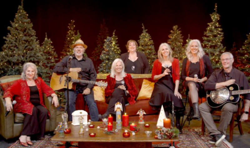 Les sept membres de la famille sont assis sur des divans avec des arbres de Noël en arrière plan.