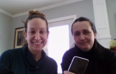 Two women on a video call, one holding up a cell phone.