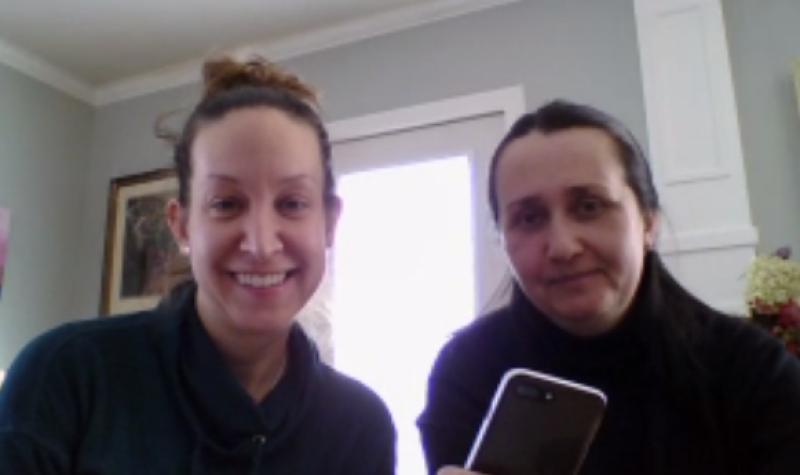 Two women on a video call, one holding up a cell phone.