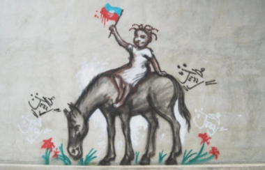 A graffiti painting shows a young Haitian girl on the back of a horse. She is holding the flag of Haiti.