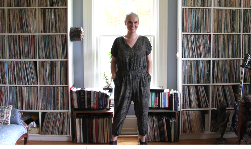 Sarah McInnis is standing in her office behind shelves of books, cds, and near guitars.