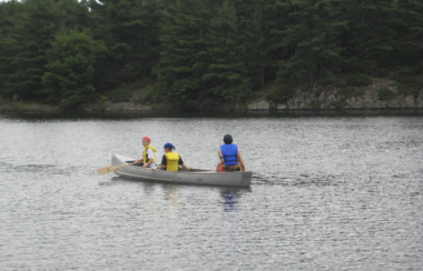Three people canoeing in a lake.