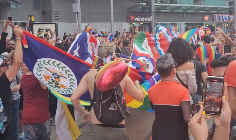 Un grupo de personas corre con una bandera gigante compuesta de banderas latinas