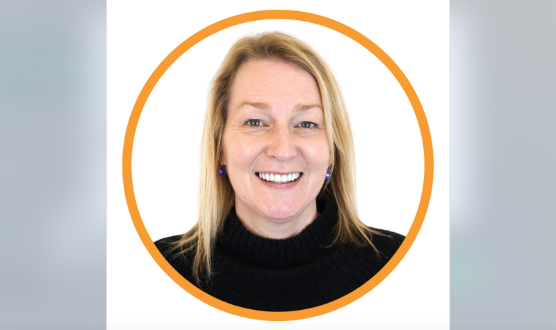 Portrait photo of climate change specialist Nancy Anningson wearing black, smiling. She has blonde hair, and is standing in front of a plain white background.