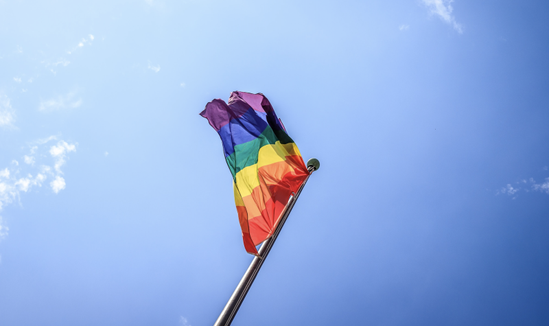 Pride flag blowing in the wind, blue sky background