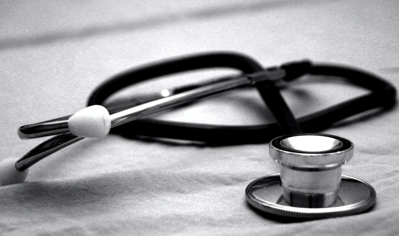 Black and white photo of a stethoscope laying tangled on a sheet