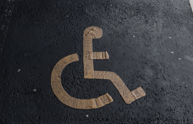 Disabled parking symbol in yellow painted on pavement to mark a disabled parking space