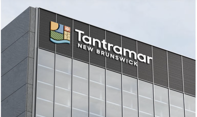 A grey building with a front wall consisting of glass floor to ceiling windows. The top two floors are dark grey with a logo and Tantramar, New Brunswick featured at the top left.