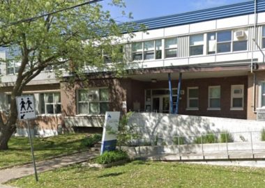 La devanture de la bâtisse de l'école secondaire Saint-Edmond à Greenfield Park. Faite de briques brunes et avec de multiples fenêtres au deuxième étage. Il y a deux arbres devant l'école.