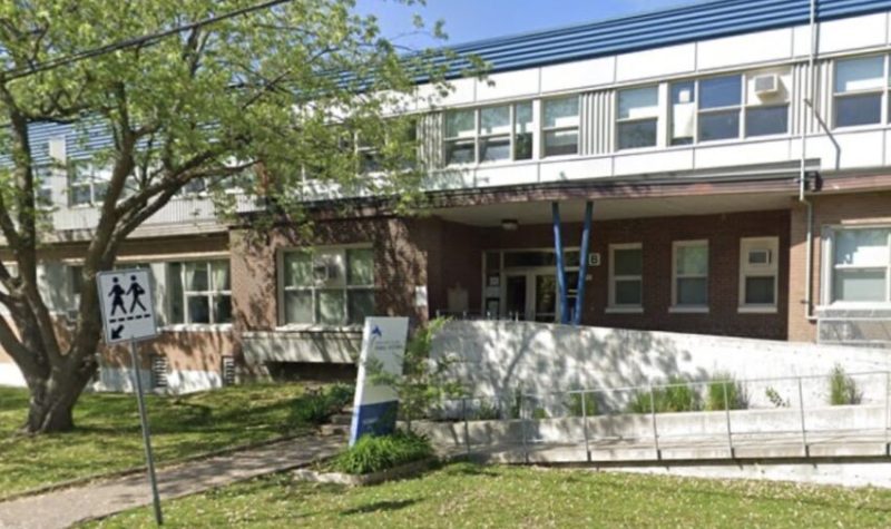 La devanture de la bâtisse de l'école secondaire Saint-Edmond à Greenfield Park. Faite de briques brunes et avec de multiples fenêtres au deuxième étage. Il y a deux arbres devant l'école.