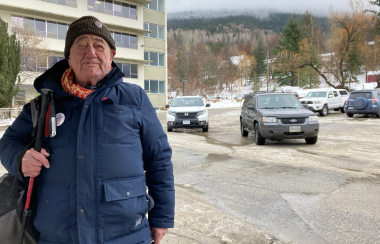 phil mader poses in blue jacket outside nelson hospital with the mountains in the background