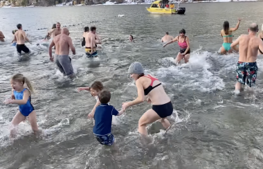 a group of people are splashing in the waters of lakeside park in nelson