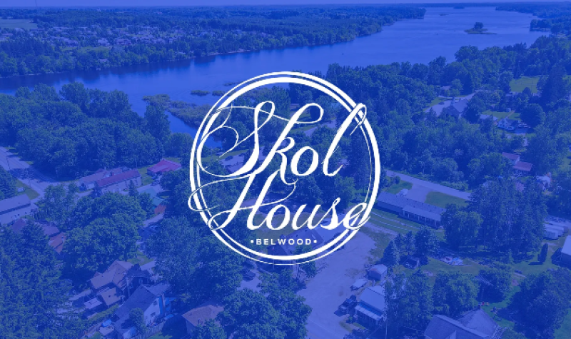 Skol house's blue cursive text-style logo is draped over a skyline view of the schoolhouse in Belwood.
