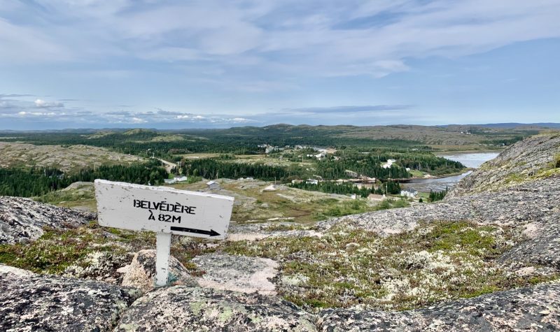 Un panneau indiquant « Belvédère à 82 mètres » avec la vue sur un village au loin.