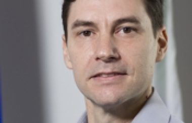 A professional headshot of Mayor Serge Newberry in front of a Quebec flag.