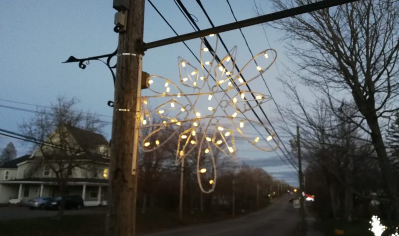 A snowflake with fairy lights hangs off a street pole.