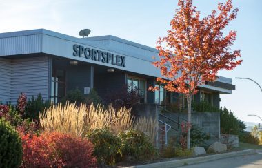 A building saying Sportsplex with orange trees in front