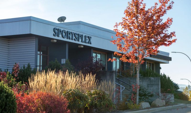 A building saying Sportsplex with orange trees in front