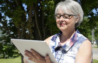 Une femme qui regarde une tablette è l'extérieur