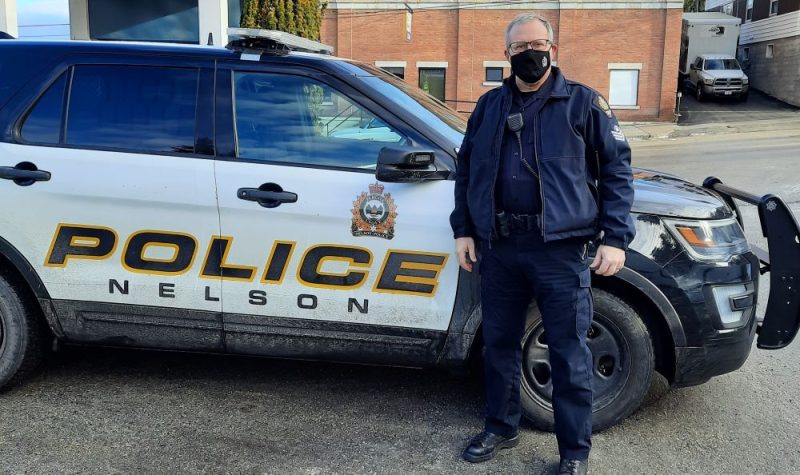 A police officer in mask in front of patrol car