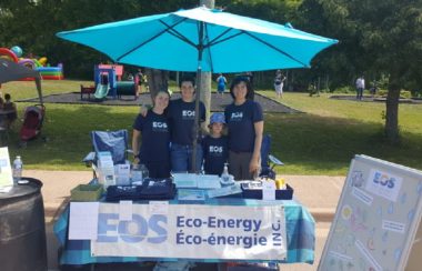 EOS Eco-Energy members stand at a booth with pamphlets.