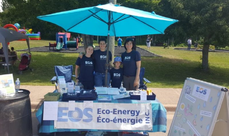 EOS Eco-Energy members stand at a booth with pamphlets.