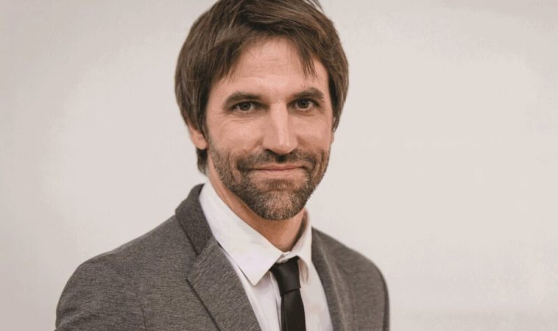 Steven Guilbeault vêtu d'une veste grise et cravate noire sur chemise blanche.